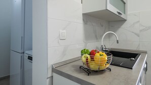 Una cucina con rivestimento in marmo, un lavello e una cesta di frutta sul piano di lavoro.