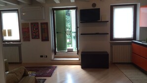 A living room with a sofa, a coffee table, a TV, and a window with blinds. - Apartment La Piu' Bella Verona (Verona)