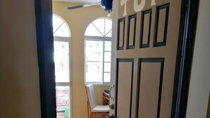 A hallway with a door labeled "TOP" leading to a room with a ceiling fan, a window, and a chair. - Tower of Prince in the Caribbean (San Rafael del Yuma)