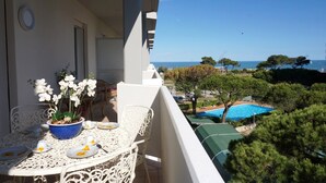 Un balcon avec une table dressée pour le dîner, offrant une vue sur une piscine et une vue dégagée sur la mer.