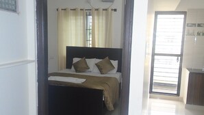A bedroom with a bed, a window, and a door leading to another room. - Siri Delight (Bengaluru)