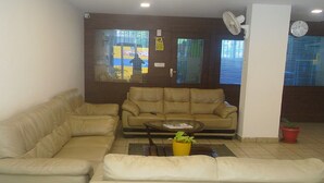 A living room with a beige sofa, a coffee table, and a yellow plant. - Siri Delight (Bengaluru)
