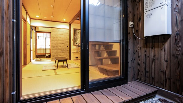 Une pièce de style japonais traditionnel, avec un sol recouvert de tatamis, une porte coulissante et un mur extérieur en bois.