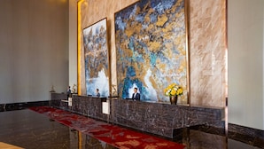 A reception area with a marble counter, two large abstract paintings, and a red carpet. - M World Hotel (Petaling Jaya)