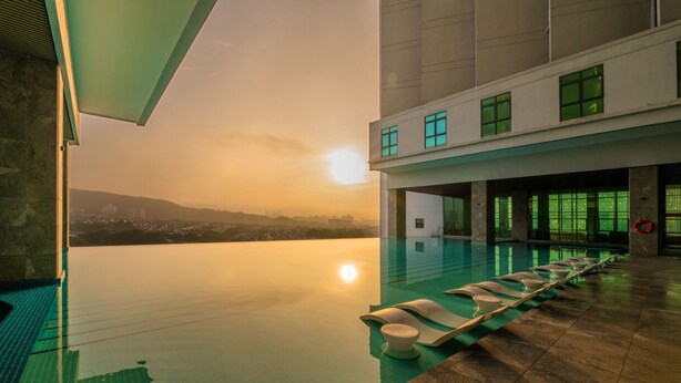 A modern indoor swimming pool with a view of a cityscape at sunset. - M World Hotel (Petaling Jaya)