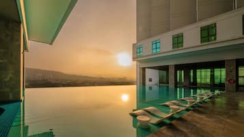Una piscina al aire libre, sombrillas, sillones reclinables de piscina