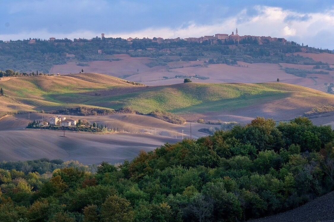 Rolling hills with a distant view of a town and a prominent building on a hill.