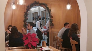 A restaurant interior with wooden beams, arched ceilings, and pendant lighting. - Hotel Piz Boè (Mazzin)