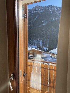 Een houten balkon met uitzicht op een besneeuwd berglandschap en een gebouw met een bord.