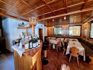 A wooden interior with a bar area, tables, and chairs. - Hotel Piz Boè (Mazzin)