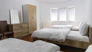 Un dormitorio con dos camas, un armario de madera y una silla.