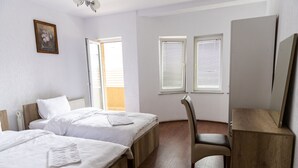 Habitación de hotel con dos camas, un escritorio de madera, una silla y una ventana con persianas.