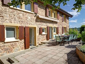 Ein Steinhaus mit Holzhörnern, eine Terrasse mit Sitzgelegenheiten und Blick ins Grüne.