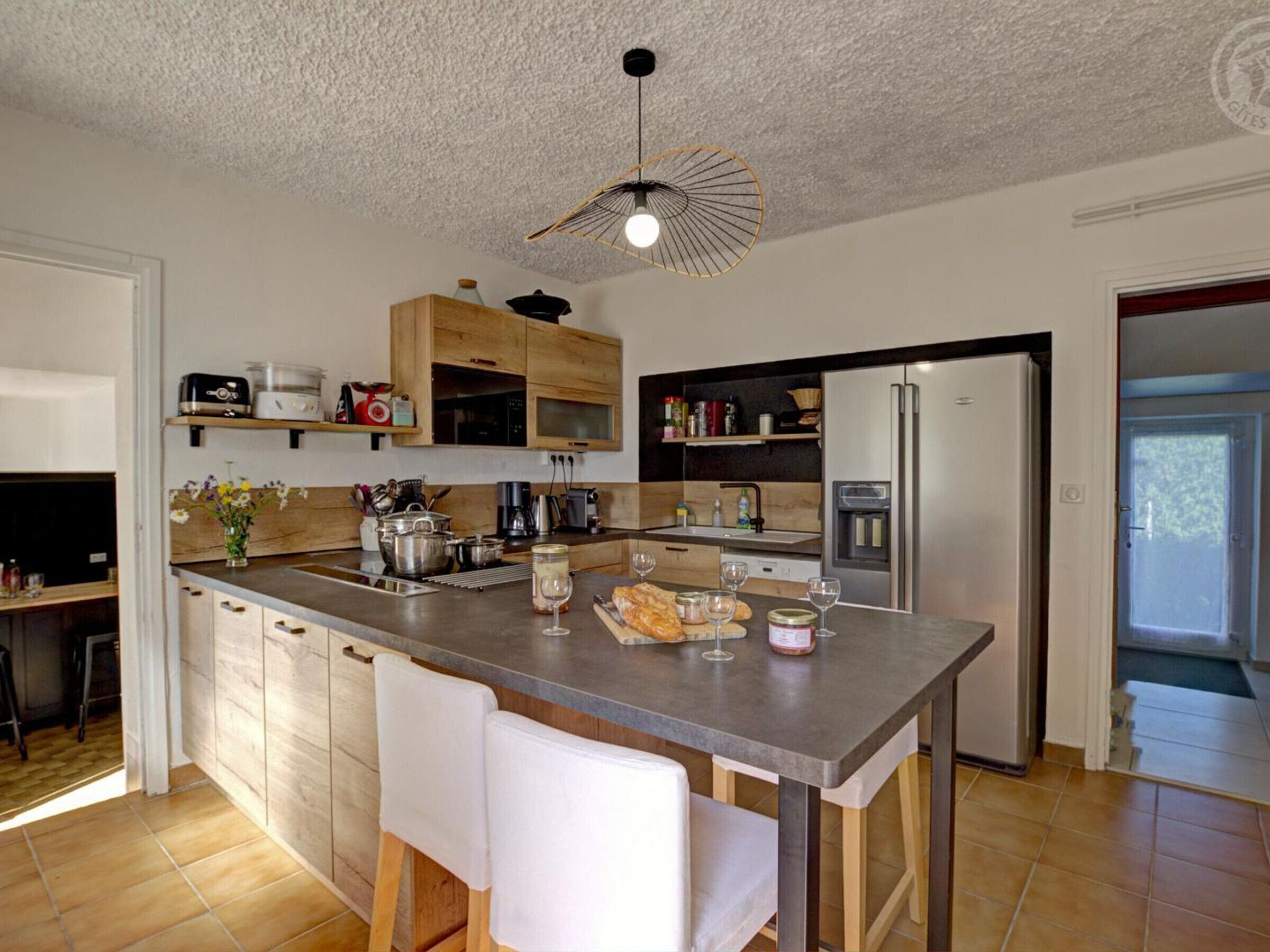 A modern kitchen with a central island, wooden cabinets, and a built-in oven.