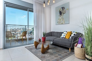 Apartamento design, 1 quarto, vista para a praia | Área de estar | TV de tela plana 55 polegadas com canais a cabo, TV