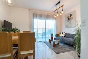 Apartamento design, 1 quarto, vista para a praia | Área de estar | TV de tela plana 55 polegadas com canais a cabo, TV