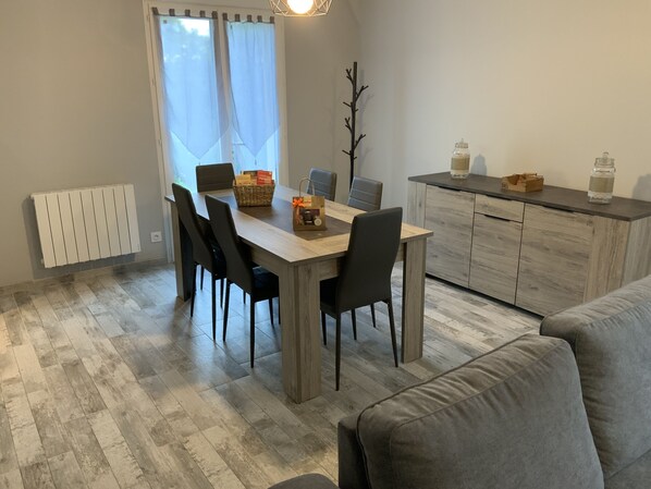 A modern dining area with a wooden table, black chairs, and a grey sofa.