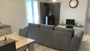 A modern living room with a grey sectional sofa, a wooden dining table, and a TV on a stand. - The house of pech dordogne (Coux-et-Bigaroque-Mouzens)