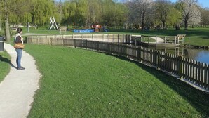 A park with a walking path, playground, and a body of water.