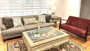 A living room with a grey sofa, a red armchair, a glass coffee table, and a patterned rug. - "The Cottage at Spruce" Tranquil, Cozy and Rustic (Burlington)
