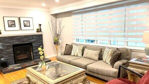 A living room with a fireplace, a sofa, a red chair, and a coffee table. - "The Cottage at Spruce" Tranquil, Cozy and Rustic (Burlington)