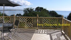 A wooden deck with a view of the sea, a table, and an umbrella.