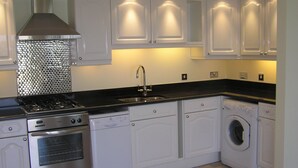 A kitchen with white cabinets, a stainless steel stove, a sink, and a washing machine.