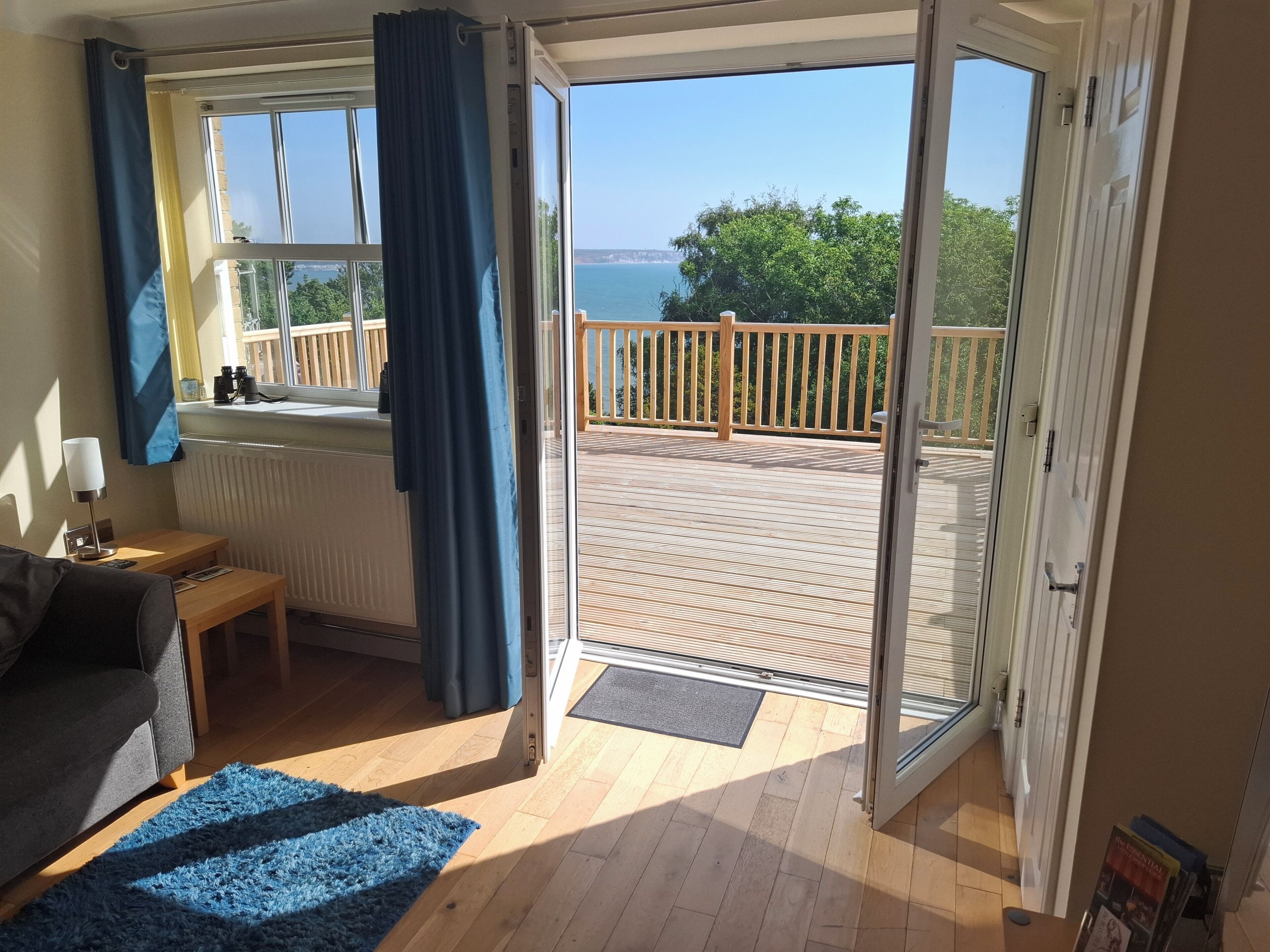 Une pièce avec vue sur la mer, une terrasse en bois et une porte-fenêtre coulissante.