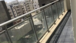A balcony with a glass railing, tiled floor, and a view of surrounding buildings. - Superb Mont Carlo Hamam Sousse vacation apartment (Hammam Sousse)