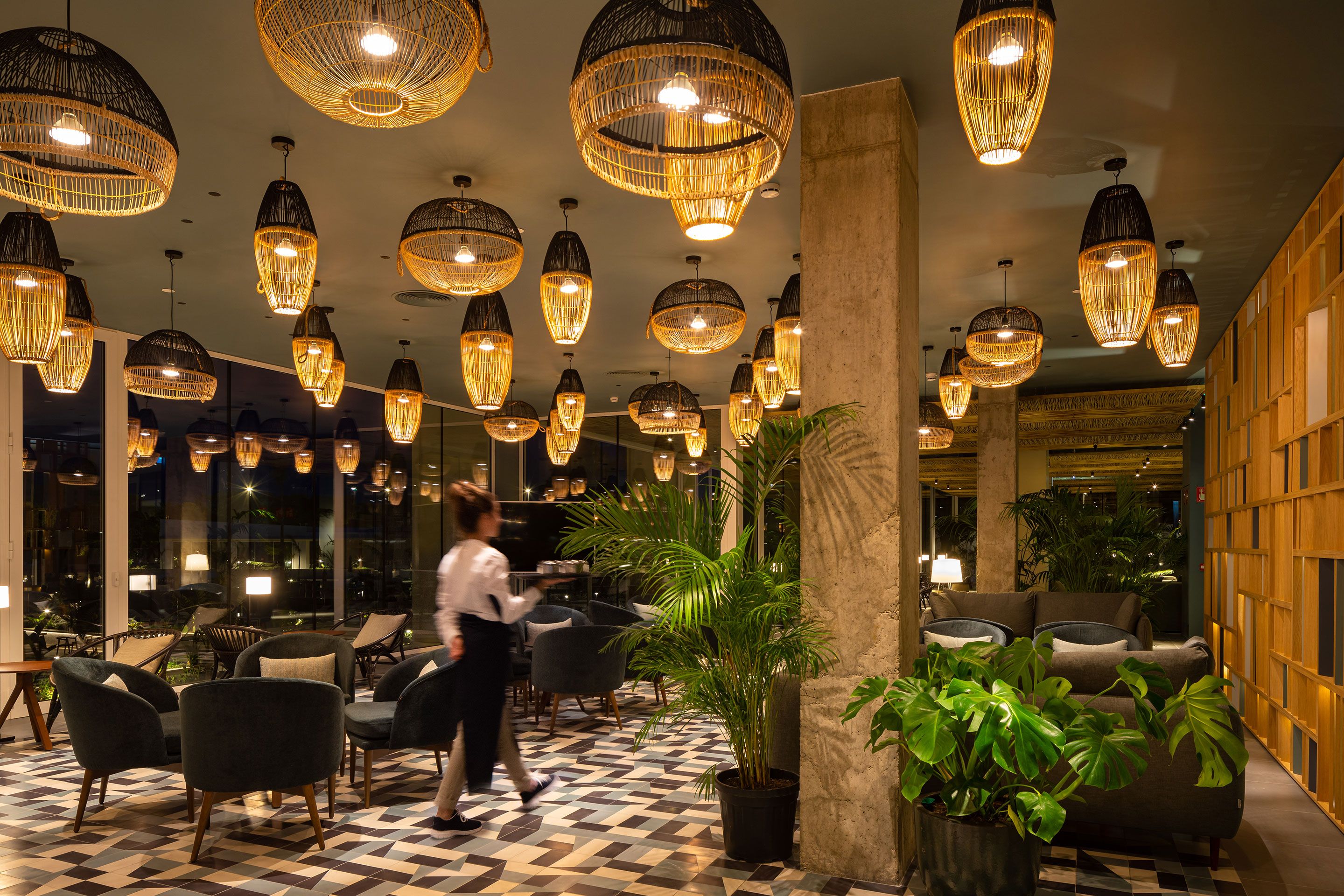 A hotel lobby with multiple seating areas, large hanging lights, and a central column.