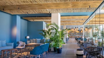 A modern lobby with a checkered floor, seating areas, and a bar in the background.