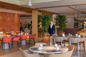 Un intérieur de restaurant moderne avec des tables rondes, des chaises et des plantes en pot.
