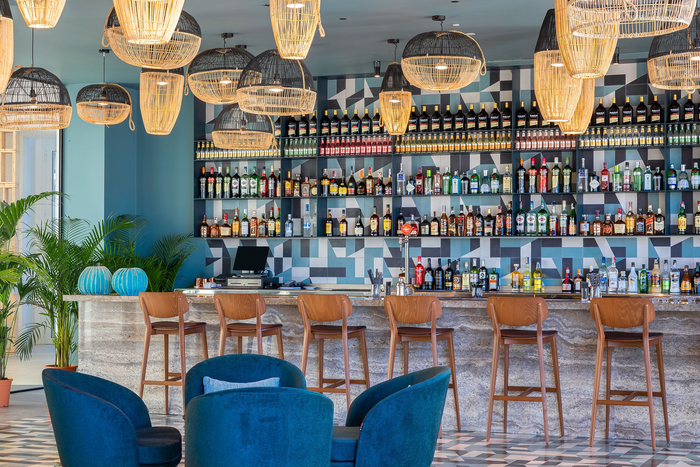 A bar area with multiple hanging light fixtures, a variety of liquor bottles on shelves, and several bar stools.