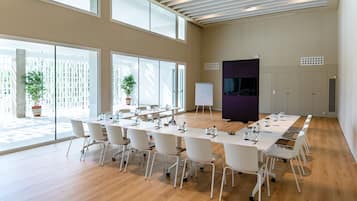 A conference room with a long table, chairs, a whiteboard, and a television screen.