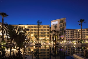 Un hotel con piscina, palmeras y cielo nocturno.