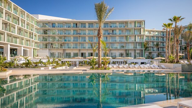 A hotel with a large pool, multiple balconies, and palm trees. - Atzavara Hotel Spa (Santa Susanna)