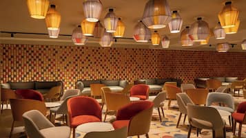 A modern interior with multiple seating areas, including sofas and chairs, and a patterned wall.