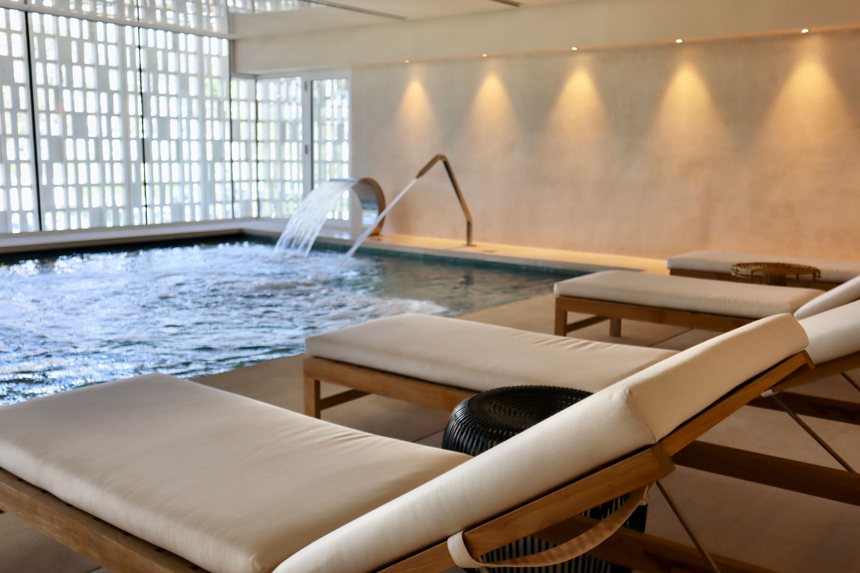 Un área de spa con hidromasaje, sillones de descanso y una fuente de agua.