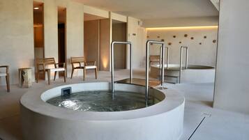 Un espace spa moderne doté d’un grand jacuzzi central, de chaises en bois et d’un design minimaliste.