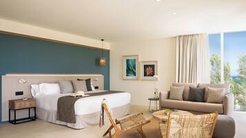 A modern hotel room with a bed, a sofa, a chair, a small table, and artwork on the walls.