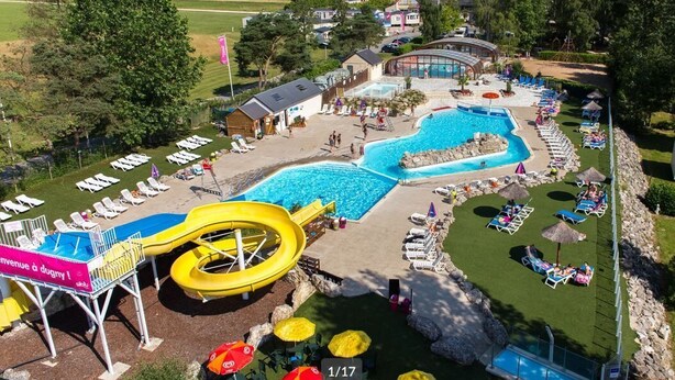 Un resort con una grande piscina, uno scivolo acquatico e numerose poltronne sdraio.