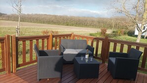 Un patio in legno con mobili in vimini e una bottiglia di vino.