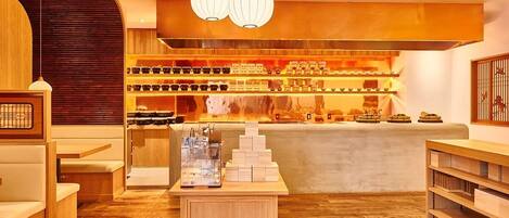 A cozy restaurant interior with wooden furniture, a central counter, and a variety of dishes displayed on shelves.