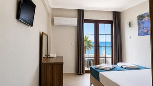 Habitación de hotel con cama, escritorio, televisión, aire acondicionado, balcón con vista al mar y un cuadro en la pared.