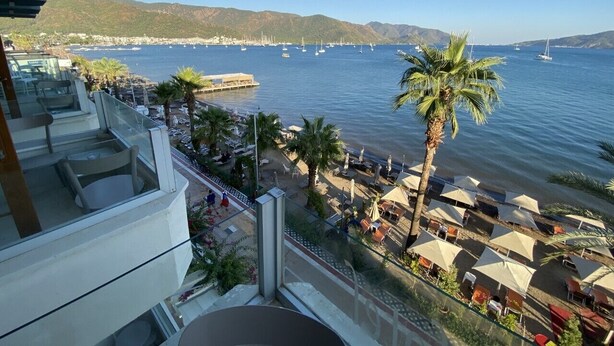 Un balcón con vista a una playa y un puerto deportivo.