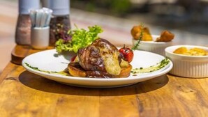 Una mesa de comedor con un plato de comida, un bol pequeño y un salero.