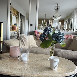 A living room with a round table, a sofa, a vase with flowers, and a chandelier.