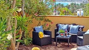 An outdoor seating area with wicker furniture, a small table with a drink, and a view of the ocean. - House CASA MAJA Costa Calma Oceanview Garden WiFi (Costa Calma)