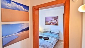 A bedroom with a bed, a nightstand, and a wall-mounted picture of a boat. - House CASA MAJA Costa Calma Oceanview Garden WiFi (Costa Calma)