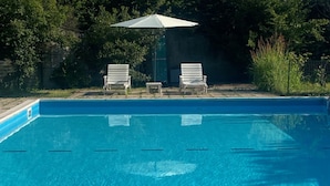 A swimming pool with two lounge chairs and a sun umbrella. - The Patio near Bergamo with a summer pool (Mozzo)